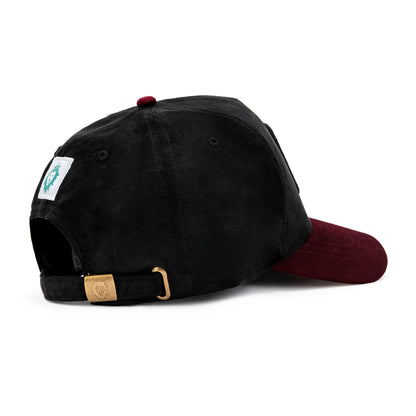 Side view of black and maroon suede cap with maroon NOGOR SHILPO embroidery and rabbit patch